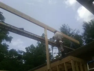 Carpenter setting a ridge beam over a new addition frame — Ice Dam Removal by Roofing Brothers in Udall