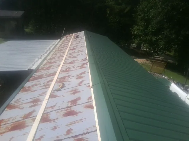 Old rusted panels beside newly installed green metal roofing — Wind Damage Roof Repair by Roofing Brothers in Udall