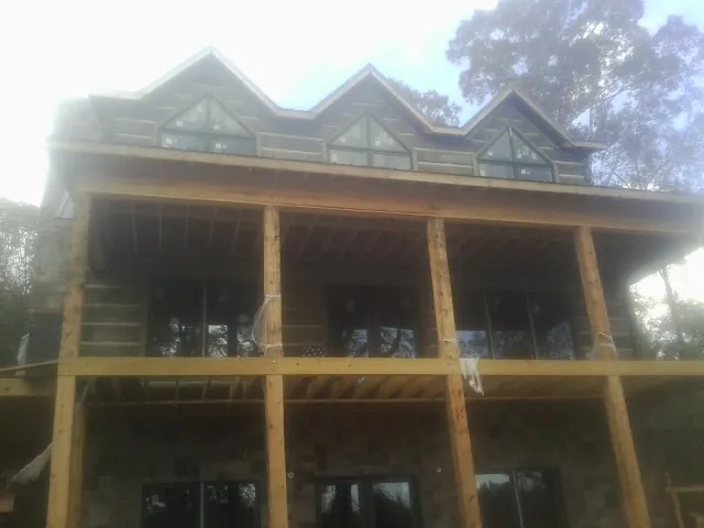 Dormers and porch framing on a large log home under construction — Roof Coating work by our crew in Udall