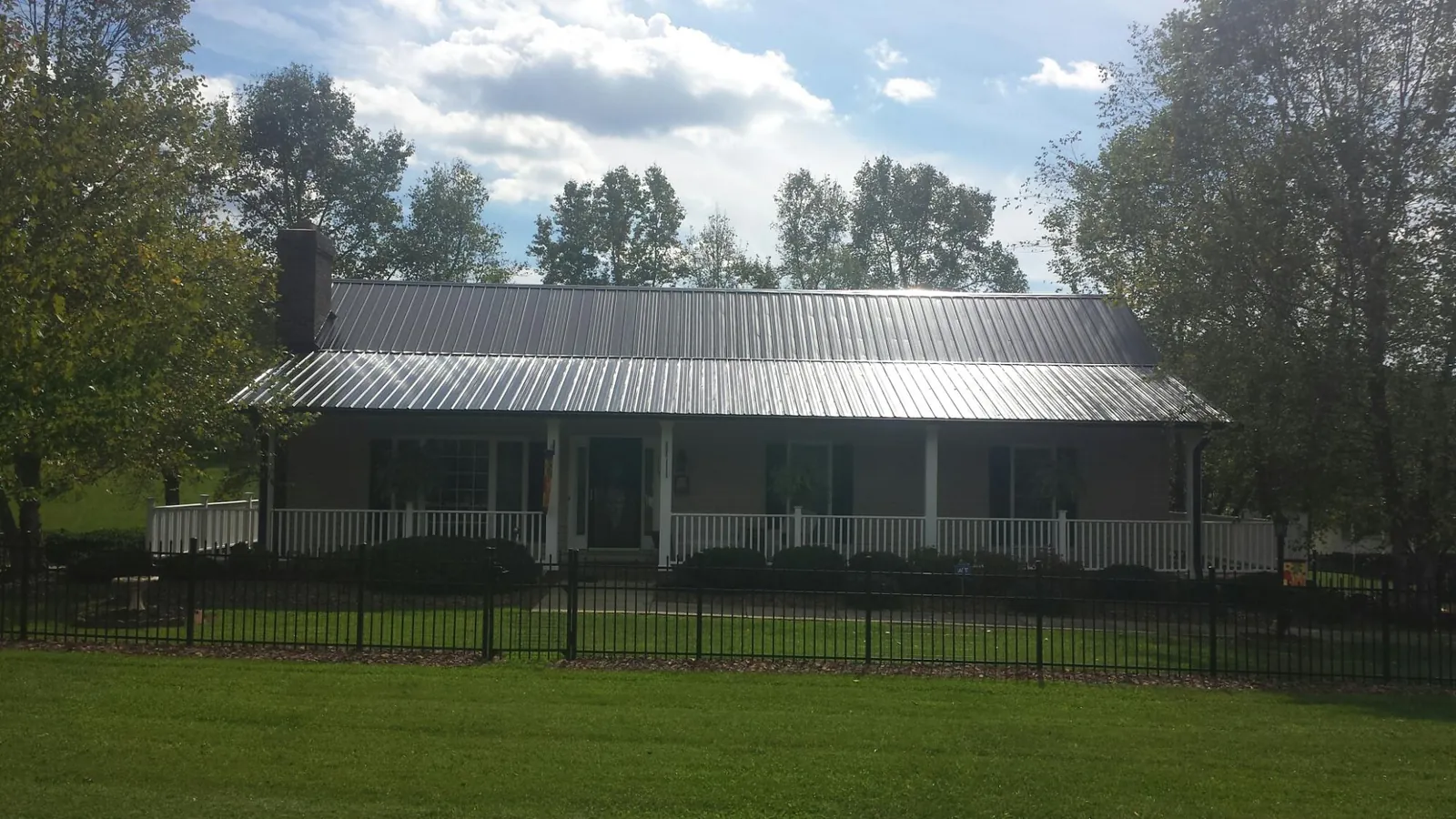 Gray metal roof on a brick ranch with a full width front porch — Gutter Guard Installation work by our crew in Udall