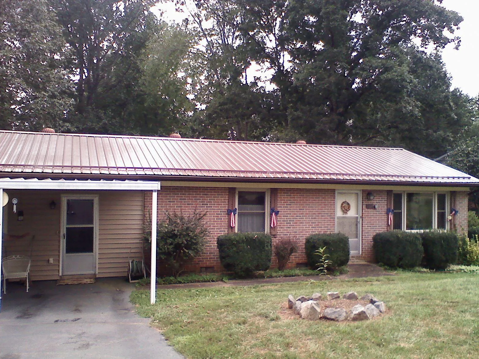 Bronze metal roof and carport on a brick ranch home — Roof Repair work by our crew in Udall