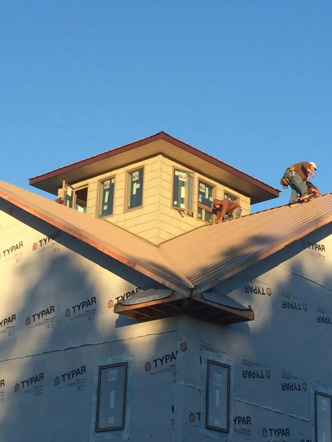 Roofers working around a rooftop cupola on a new metal roof at sunset — Roof Waterproofing in Udall by Roofing Brothers